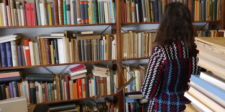 Kundin im Antiquariat vor vollem Bücherregal