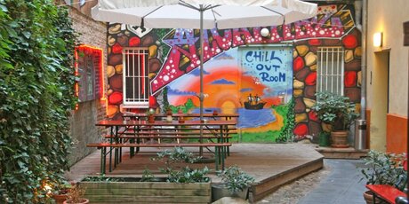 Sitzecke vor Graffitiwand im Innenhof des Hostels