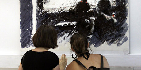 Zwei junge Frauen betrachten ein Bild in einer Galereie
