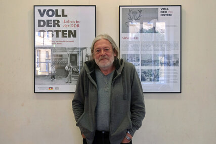 Fotograf Harald Hauswald vor Ausstellungsplakat