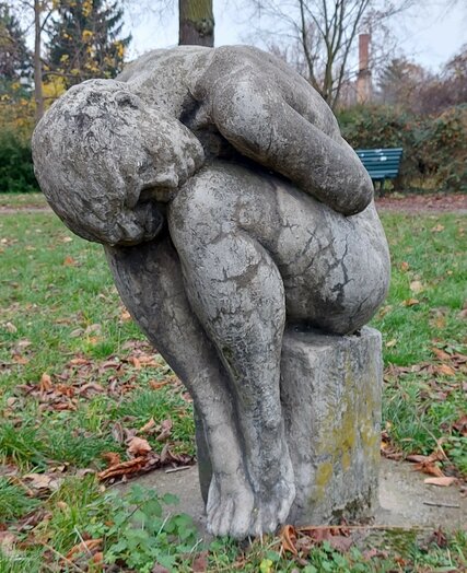Standort: Hermann-Hesse-Straße 18/Güllweg, Grünfläche, "Sitzende/Kauernde", Künstler: Rolf Winkler (1930–2001), Datierung: 1983, Aufstellung: 1985, Material: Beton
