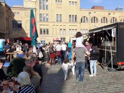 Street Food Markt auf dem Hofn der KulturBrauerei. Besucher an Ständen und beim Essen.