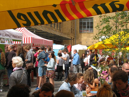Besucher vor Ständen und an Tischen auf dem Street Food Markt