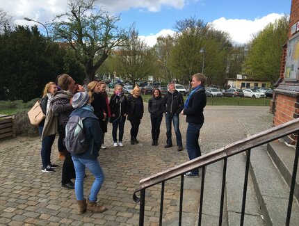 Stadtführerin A. Zimmermann mit Touristengruppe vor dem Eingang einer Kirche bei Stadtbilderklärung.