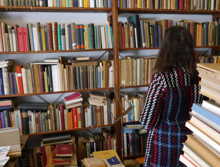 Kundin im Antiquariat vor vollem Bücherregal