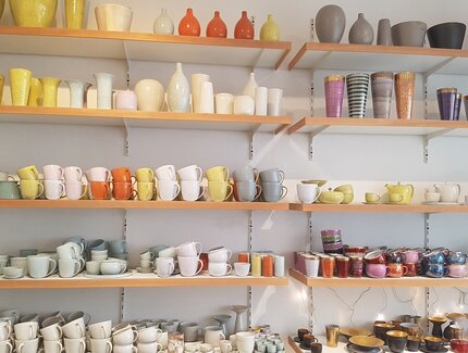 vielfarbige Keramikwaren auf Wandregalen bei Landbeck Keramik