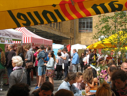 Besucher vor Ständen und an Tischen auf dem Street Food Markt